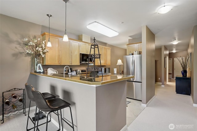15000 Juanita Dr NE Unit 309, Kenmore, WA 98028 - kitchen with appliances with stainless steel finishes, light brown cabinetry, a peninsula, a kitchen breakfast bar, and light carpet
