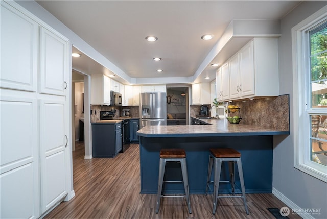 16420 92nd Avenue Ct E, Puyallup, WA 98375 - kitchen featuring black appliances, white cabinetry, backsplash, a breakfast bar, and dark wood-type flooring