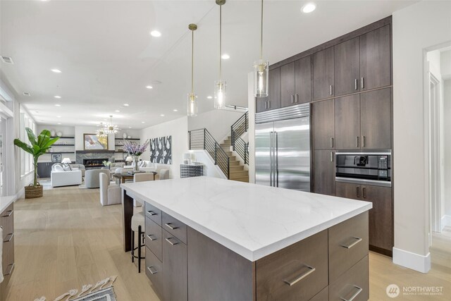 1806 154th Ave SE, Bellevue, WA 98007 - kitchen with built in appliances, recessed lighting, a kitchen island, dark brown cabinetry, and light wood-type flooring