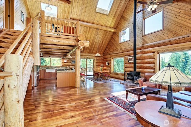 194 Protection Ridge Dr, Port Townsend, WA 98368 - living area featuring high vaulted ceiling, a wood stove, rustic walls, a skylight, and light wood-style floors
