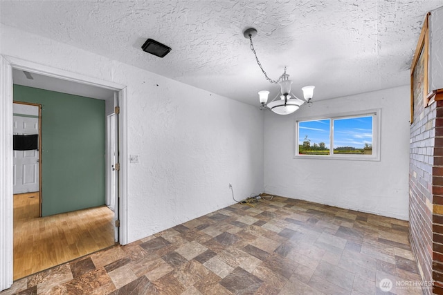 8739 F And S Grade Rd, Sedro Woolley, WA 98284 - unfurnished room featuring a chandelier, stone finish floors, a textured wall, and a textured ceiling