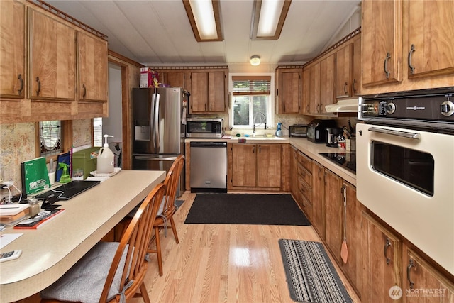 8031 Fir Tree Ln, Lake Stevens, WA 98258 - kitchen featuring stainless steel appliances, brown cabinetry, light wood-style flooring, light countertops, and under cabinet range hood