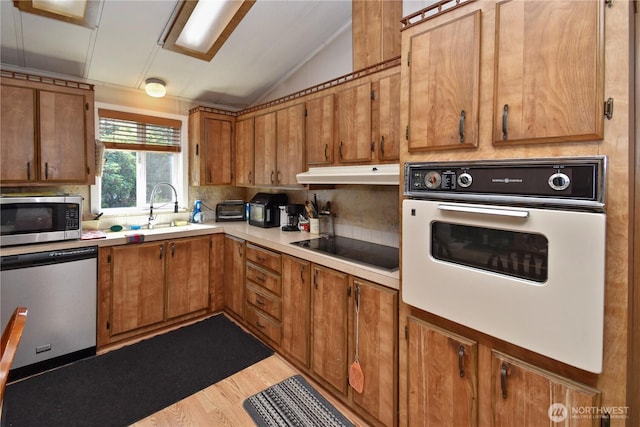 8031 Fir Tree Ln, Lake Stevens, WA 98258 - kitchen with appliances with stainless steel finishes, under cabinet range hood, vaulted ceiling, brown cabinetry, and light countertops