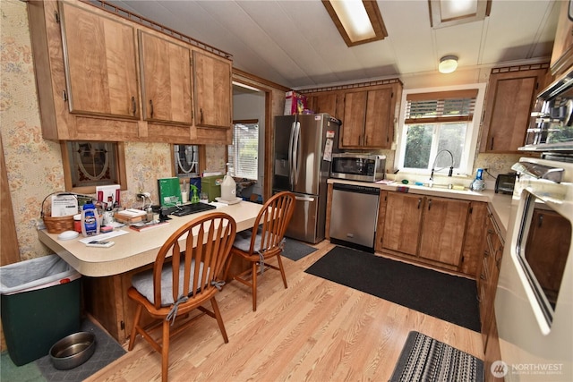 8031 Fir Tree Ln, Lake Stevens, WA 98258 - kitchen featuring appliances with stainless steel finishes, brown cabinets, light wood-style flooring, light countertops, and an office area