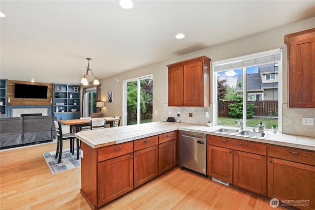 12115 184th Ave E, Bonney Lake, WA 98391 - kitchen featuring stainless steel dishwasher, a peninsula, light wood-style floors, open floor plan, and brown cabinetry