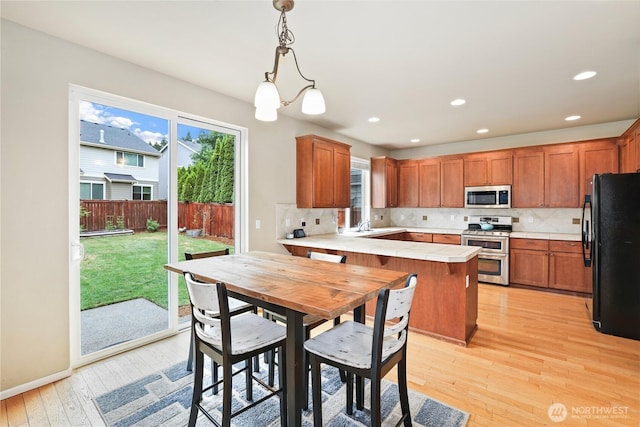 12115 184th Ave E, Bonney Lake, WA 98391 - kitchen featuring stainless steel appliances, a peninsula, light wood-style flooring, healthy amount of natural light, and recessed lighting