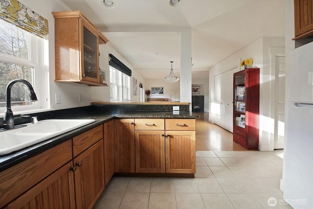 4876 Breezefair Rd, Freeland, WA 98249 - kitchen with brown cabinetry, glass insert cabinets, light tile patterned flooring, freestanding refrigerator, and dark countertops