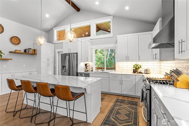 989 Lakewood Ln, Bellingham, WA 98229 - kitchen featuring stainless steel appliances, wall chimney exhaust hood, beam ceiling, a kitchen breakfast bar, and light stone counters