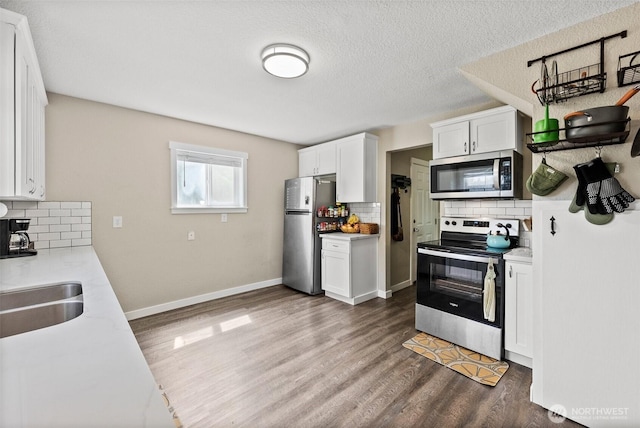 9413 356th Street Ct S, Roy, WA 98558 - kitchen featuring stainless steel appliances, backsplash, light countertops, white cabinetry, and dark wood-type flooring