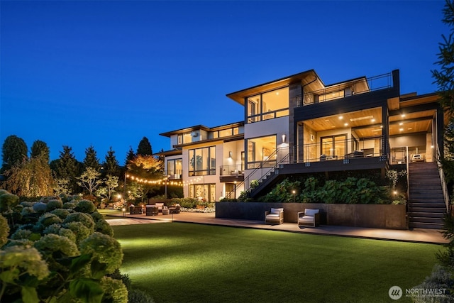 9001 NE 14th St, Clyde Hill, WA 98004 - back of house at night with stairs, a balcony, stucco siding, and a patio