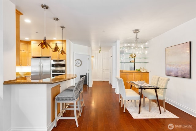 719 2nd Ave W Unit 101, Seattle, WA 98119 - kitchen with appliances with stainless steel finishes, dark wood-type flooring, hanging light fixtures, a chandelier, and a kitchen breakfast bar