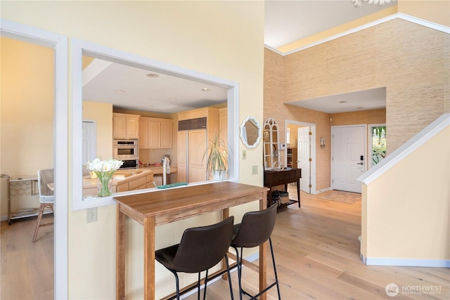 95 Martingale Pl, Port Ludlow, WA 98365 - kitchen featuring light brown cabinetry, paneled built in refrigerator, light wood-style flooring, a towering ceiling, and stainless steel double oven