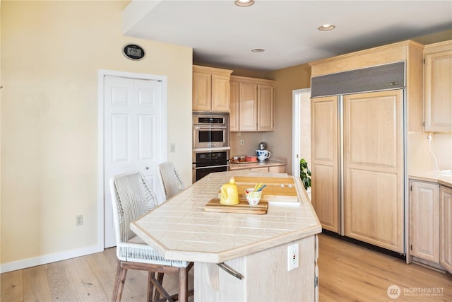 95 Martingale Pl, Port Ludlow, WA 98365 - kitchen with paneled built in fridge, tile countertops, light brown cabinets, light wood finished floors, and recessed lighting