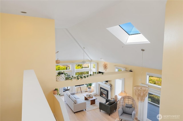 95 Martingale Pl, Port Ludlow, WA 98365 - living area featuring high vaulted ceiling, a skylight, a glass covered fireplace, and wood finished floors