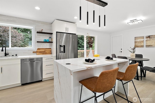 6347 121st Ave SE, Bellevue, WA 98006 - kitchen featuring stainless steel appliances, a kitchen bar, light wood finished floors, a kitchen island, and backsplash
