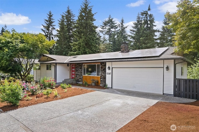 6347 121st Ave SE, Bellevue, WA 98006 - view of front of home with a garage, solar panels, concrete driveway, a chimney, and stone siding