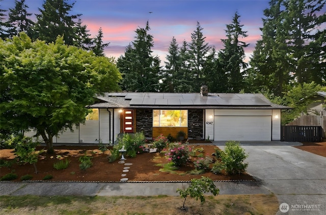 6347 121st Ave SE, Bellevue, WA 98006 - view of front facade featuring concrete driveway, an attached garage, solar panels, and stone siding