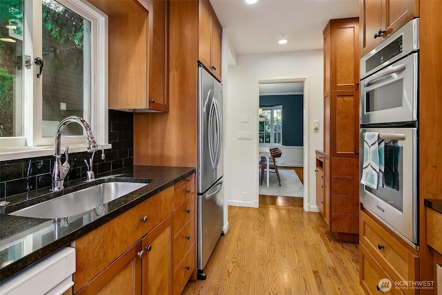 4412 43rd Ave NE, Seattle, WA 98105 - kitchen with appliances with stainless steel finishes, light wood-style flooring, brown cabinets, backsplash, and dark stone countertops