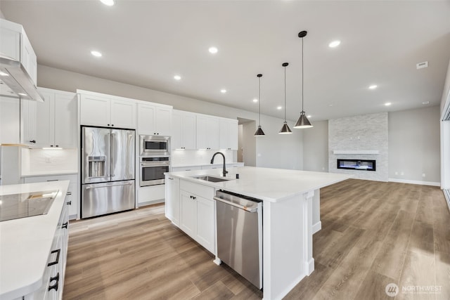 10630 134th Dr NE Unit 112, Lake Stevens, WA 98258 - kitchen with appliances with stainless steel finishes, light wood finished floors, white cabinets, a center island with sink, and backsplash