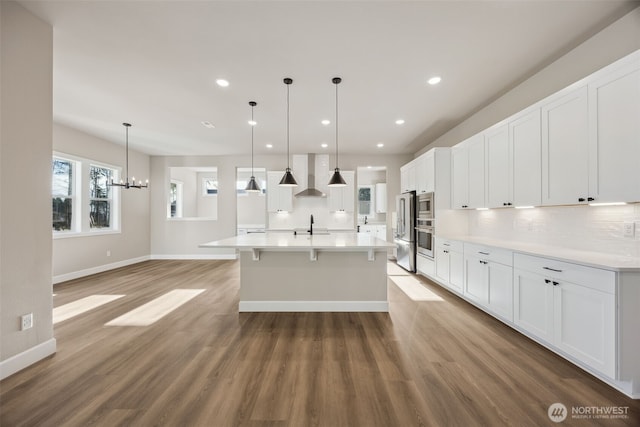 10630 134th Dr NE Unit 112, Lake Stevens, WA 98258 - kitchen with wall chimney exhaust hood, appliances with stainless steel finishes, light wood-style flooring, decorative backsplash, and white cabinetry