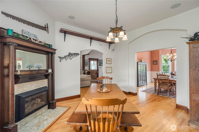 404 W Marcy Ave, Montesano, WA 98563 - dining area featuring a chandelier, arched walkways, light wood-style flooring, and a fireplace with flush hearth