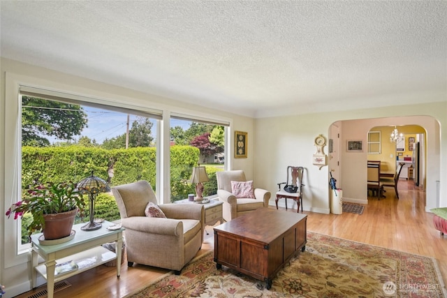 910 Crestline Dr, Longview, WA 98632 - living room with arched walkways, a textured ceiling, a chandelier, and light wood-style floors
