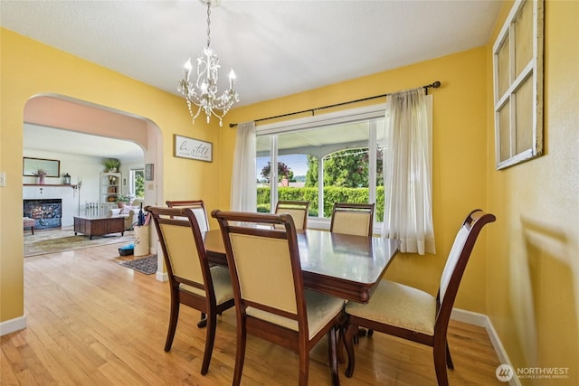 910 Crestline Dr, Longview, WA 98632 - dining room with arched walkways, wood finished floors, a chandelier, and a fireplace