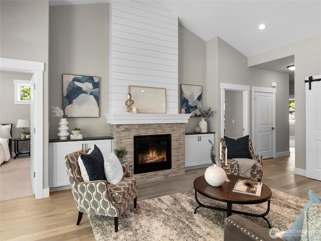 13809 119th Street Ct NW, Gig Harbor, WA 98329 - living area with a barn door, light wood finished floors, high vaulted ceiling, a fireplace, and recessed lighting