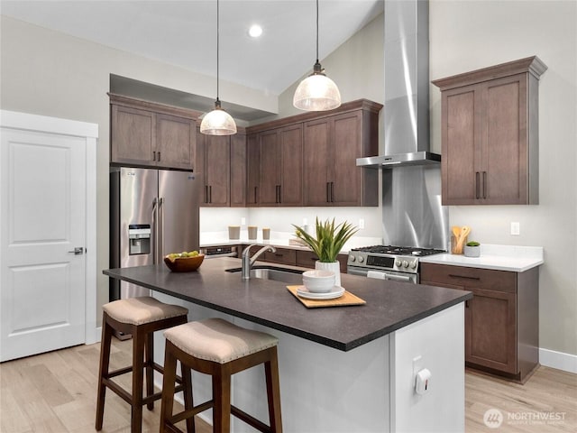 13809 119th Street Ct NW, Gig Harbor, WA 98329 - kitchen with wall chimney exhaust hood, appliances with stainless steel finishes, vaulted ceiling, light wood-style floors, and decorative light fixtures
