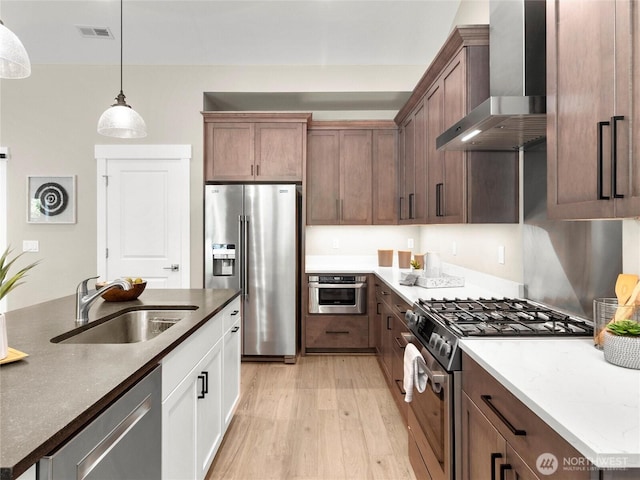 13809 119th Street Ct NW, Gig Harbor, WA 98329 - kitchen with wall chimney exhaust hood, stainless steel appliances, light wood finished floors, decorative light fixtures, and dark stone counters