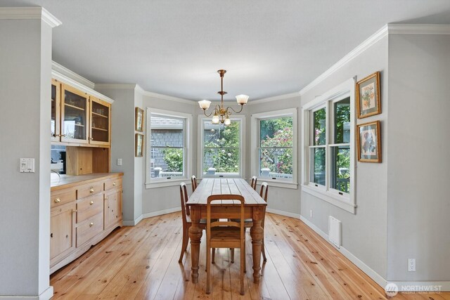 909 308th St NE, Stanwood, WA 98282 - dining room featuring light wood-style flooring, plenty of natural light, a chandelier, and crown molding