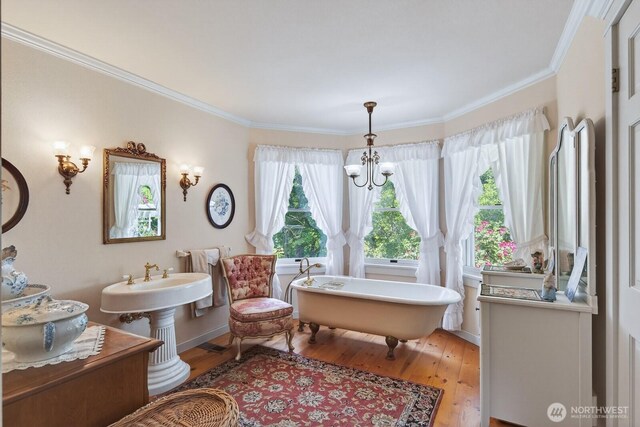 909 308th St NE, Stanwood, WA 98282 - bathroom with ornamental molding, hardwood / wood-style flooring, a soaking tub, and a chandelier