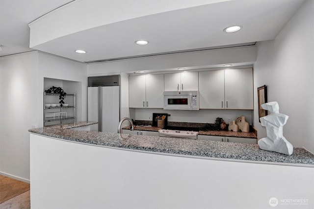 2000 1st Ave Unit 703, Seattle, WA 98121 - kitchen featuring white appliances, dark stone countertops, recessed lighting, and white cabinetry