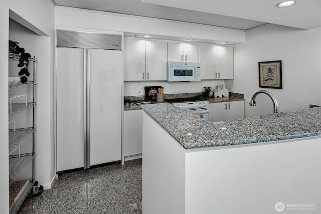 2000 1st Ave Unit 703, Seattle, WA 98121 - kitchen with white appliances, white cabinetry, dark stone counters, recessed lighting, and a peninsula