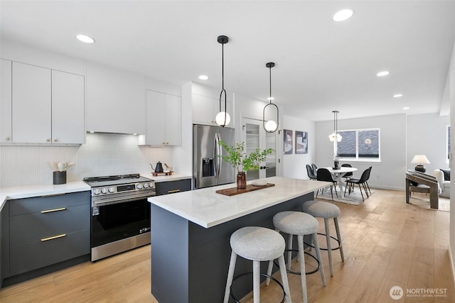 3424 20th Ave S, Seattle, WA 98144 - kitchen featuring stainless steel appliances, a breakfast bar, light wood-type flooring, a kitchen island, and pendant lighting