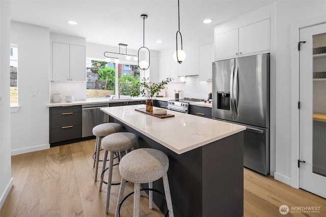 3424 20th Ave S, Seattle, WA 98144 - kitchen featuring stainless steel appliances, tasteful backsplash, a kitchen breakfast bar, a center island, and light wood-type flooring