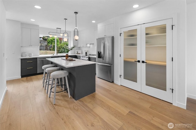 3424 20th Ave S, Seattle, WA 98144 - kitchen featuring stainless steel appliances, a kitchen island, a kitchen bar, light wood-style flooring, and light countertops