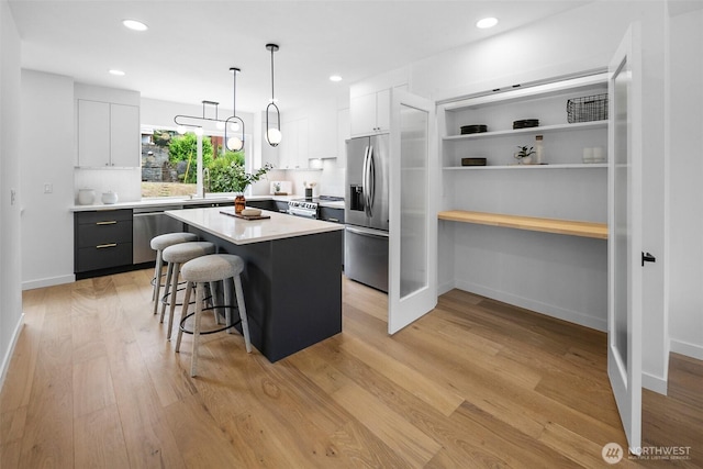 3424 20th Ave S, Seattle, WA 98144 - kitchen with stainless steel appliances, a kitchen breakfast bar, light countertops, a center island, and light wood finished floors