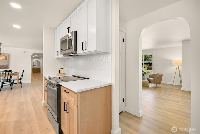 16740 Dunbar Rd, Mount Vernon, WA 98273 - kitchen featuring stainless steel appliances, arched walkways, light wood-type flooring, recessed lighting, and light countertops