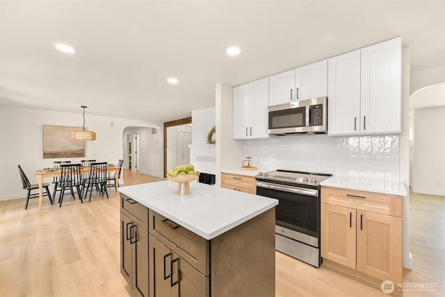 16740 Dunbar Rd, Mount Vernon, WA 98273 - kitchen with appliances with stainless steel finishes, arched walkways, light wood-style floors, a center island, and light countertops