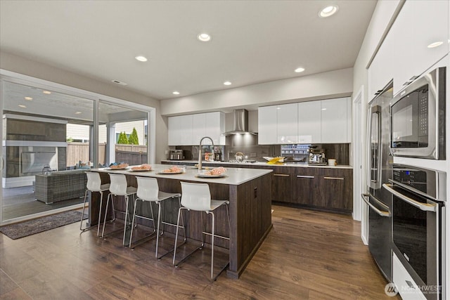 35404 55th Ave S, Auburn, WA 98001 - kitchen with modern cabinets, stainless steel appliances, wall chimney exhaust hood, dark brown cabinetry, and a breakfast bar