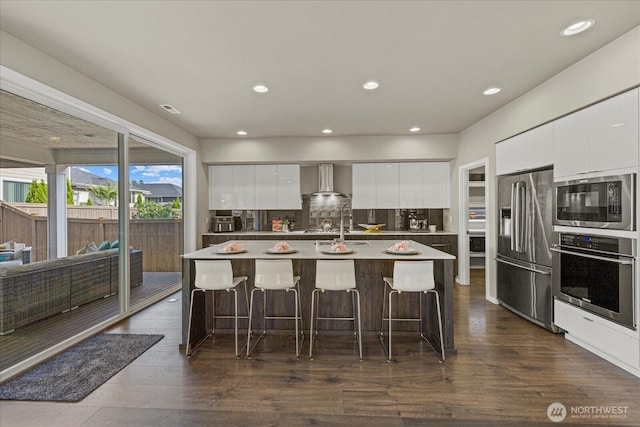 35404 55th Ave S, Auburn, WA 98001 - kitchen with stainless steel appliances, modern cabinets, wall chimney range hood, a kitchen breakfast bar, and dark wood-type flooring