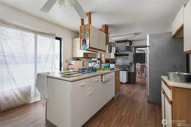 715 Locust St, Omak, WA 98841 - kitchen with dark wood-style floors, a ceiling fan, light countertops, and white cabinetry