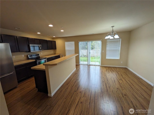 1077 Hiton Cir, Dupont, WA 98327 - kitchen with stainless steel appliances, light countertops, dark wood-type flooring, a chandelier, and an island with sink