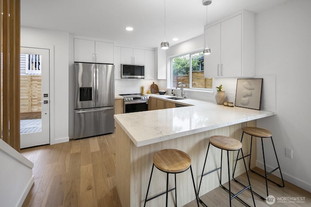 3422 20th Ave S, Seattle, WA 98144 - kitchen featuring stainless steel appliances, a peninsula, light wood-type flooring, a kitchen breakfast bar, and recessed lighting