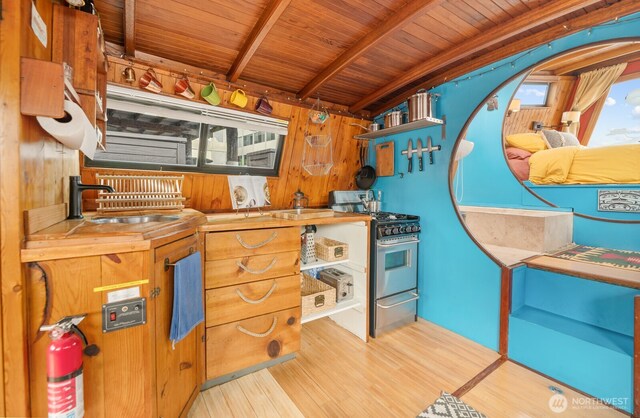 2550-2738 Westlake Ave N Unit 01-117, Seattle, WA 98109 - kitchen featuring stainless steel gas range oven, wood finished floors, a wood ceiling with exposed beams, wood walls, and healthy amount of natural light