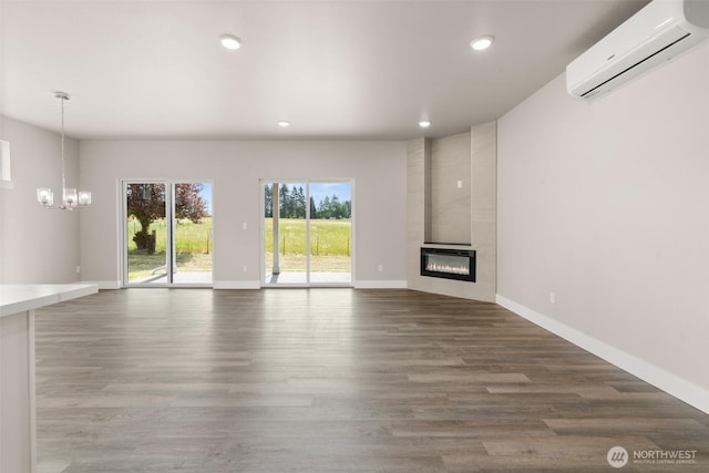 2122 Hawks View Ln, Winlock, WA 98596 - unfurnished living room with a wall unit AC, a chandelier, a fireplace, wood finished floors, and recessed lighting