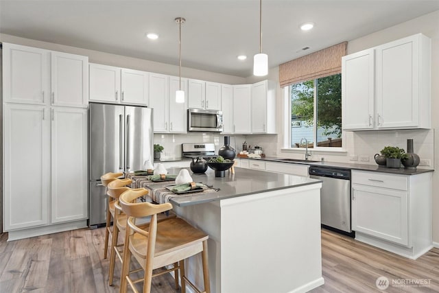 8705 126th Street Ct E, Puyallup, WA 98374 - kitchen with appliances with stainless steel finishes, white cabinets, tasteful backsplash, light wood-style flooring, and recessed lighting