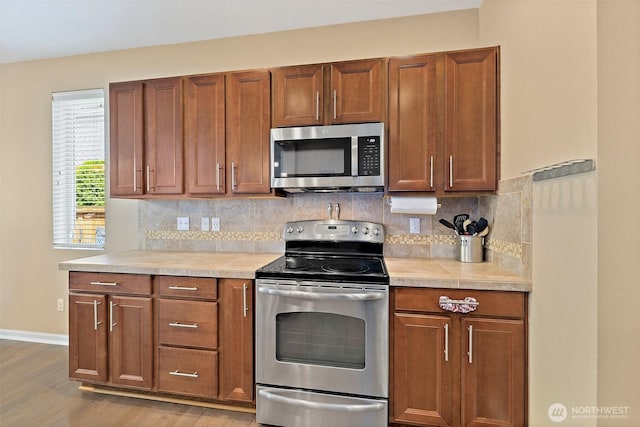 16922 SE 262nd St, Covington, WA 98042 - kitchen featuring appliances with stainless steel finishes, light countertops, tasteful backsplash, and wood finished floors