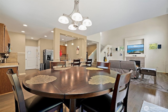 16922 SE 262nd St, Covington, WA 98042 - dining room with wood-type flooring, a chandelier, stairway, a tiled fireplace, and recessed lighting